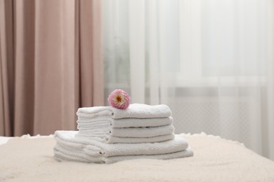Photo of Stack of white terry towels and dahlia flower on bed indoors. Space for text