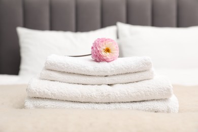 Photo of Stack of white terry towels and dahlia flower on bed, closeup