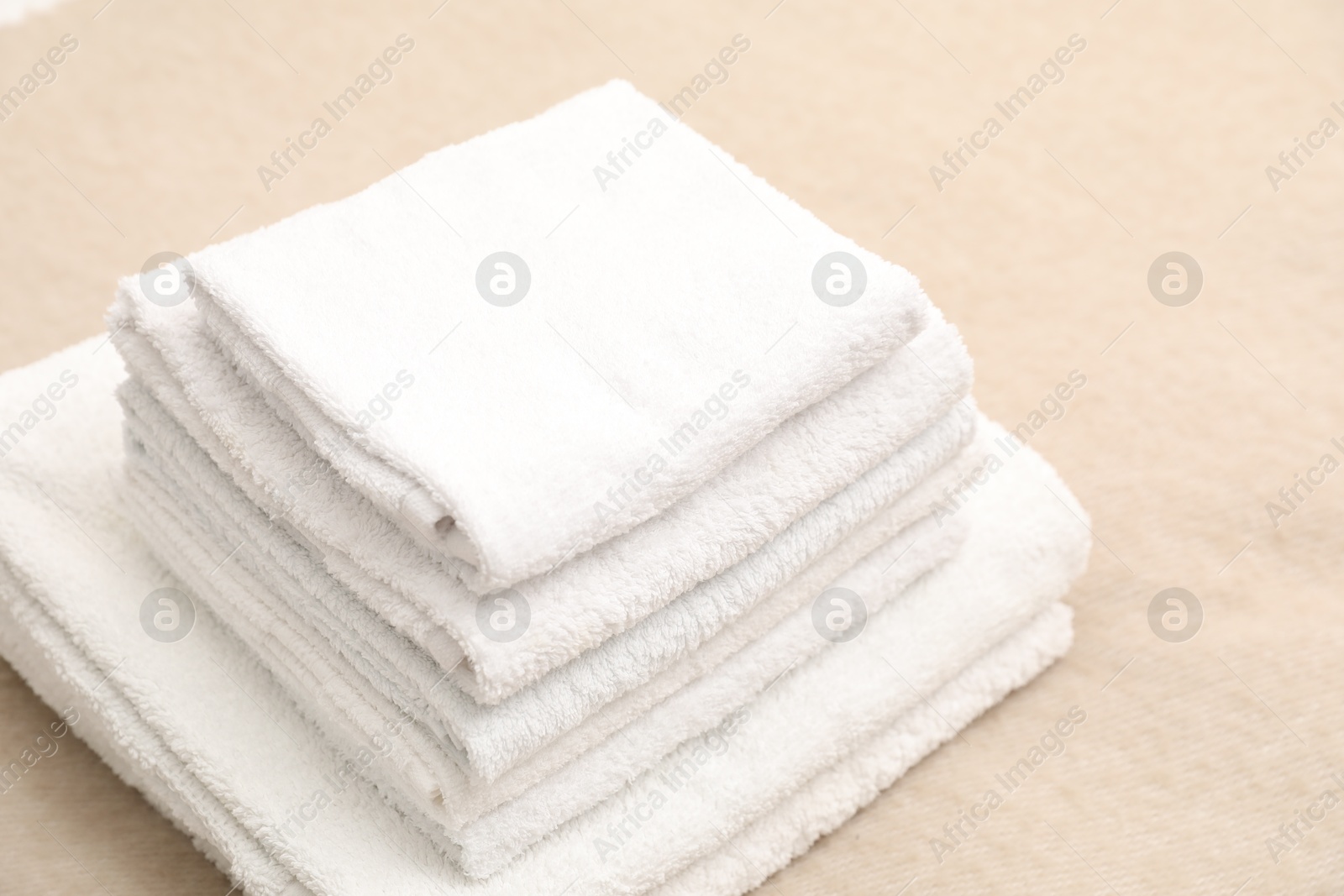 Photo of Stack of white terry towels on beige blanket, closeup