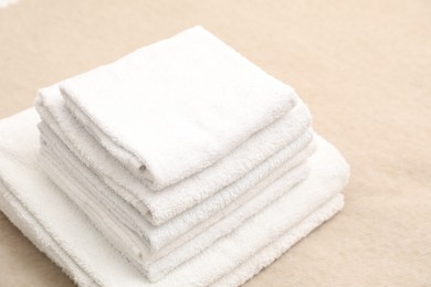 Photo of Stack of white terry towels on beige blanket, closeup