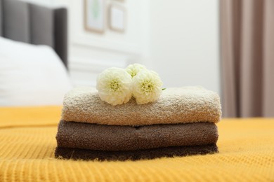 Photo of Stack of terry towels and dahlia flowers on bed indoors, closeup