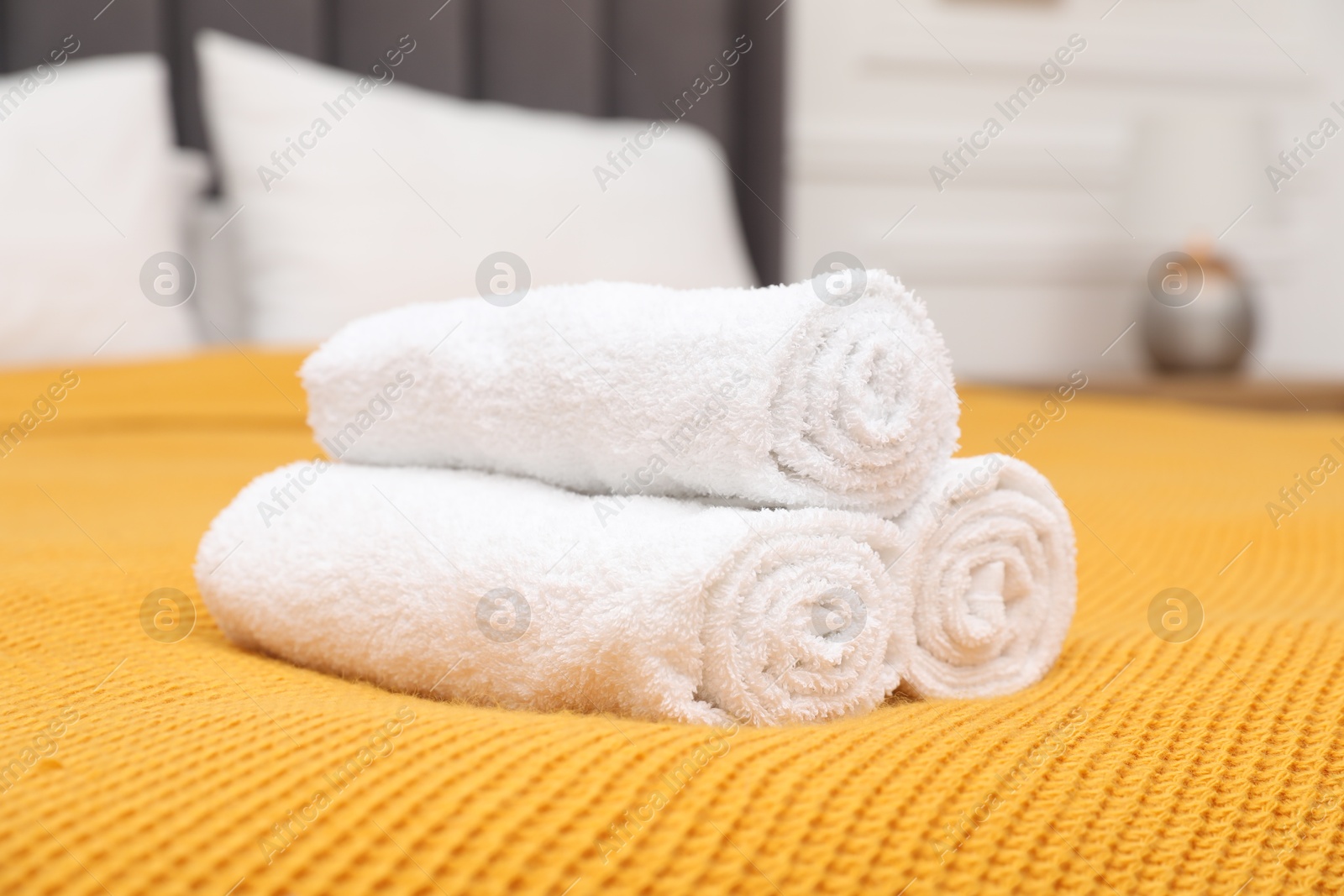 Photo of Rolled white terry towels on bed indoors, closeup