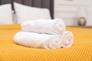 Photo of Rolled white terry towels on bed indoors, closeup