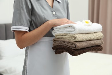Photo of Chambermaid with stack of terry towels and plumeria flower in hotel room, closeup