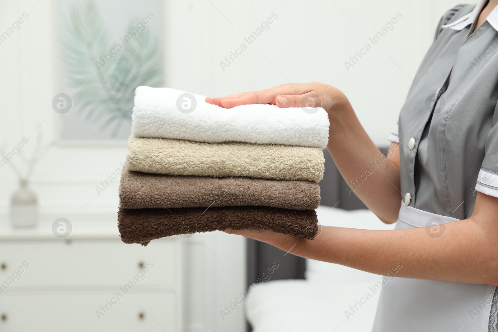 Photo of Chambermaid with stack of terry towels in hotel room, closeup