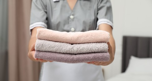 Photo of Chambermaid with stack of terry towels in hotel room, closeup