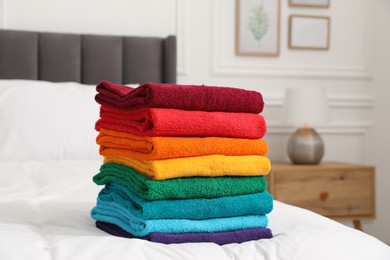Photo of Stack of bright terry towels on bed indoors, closeup
