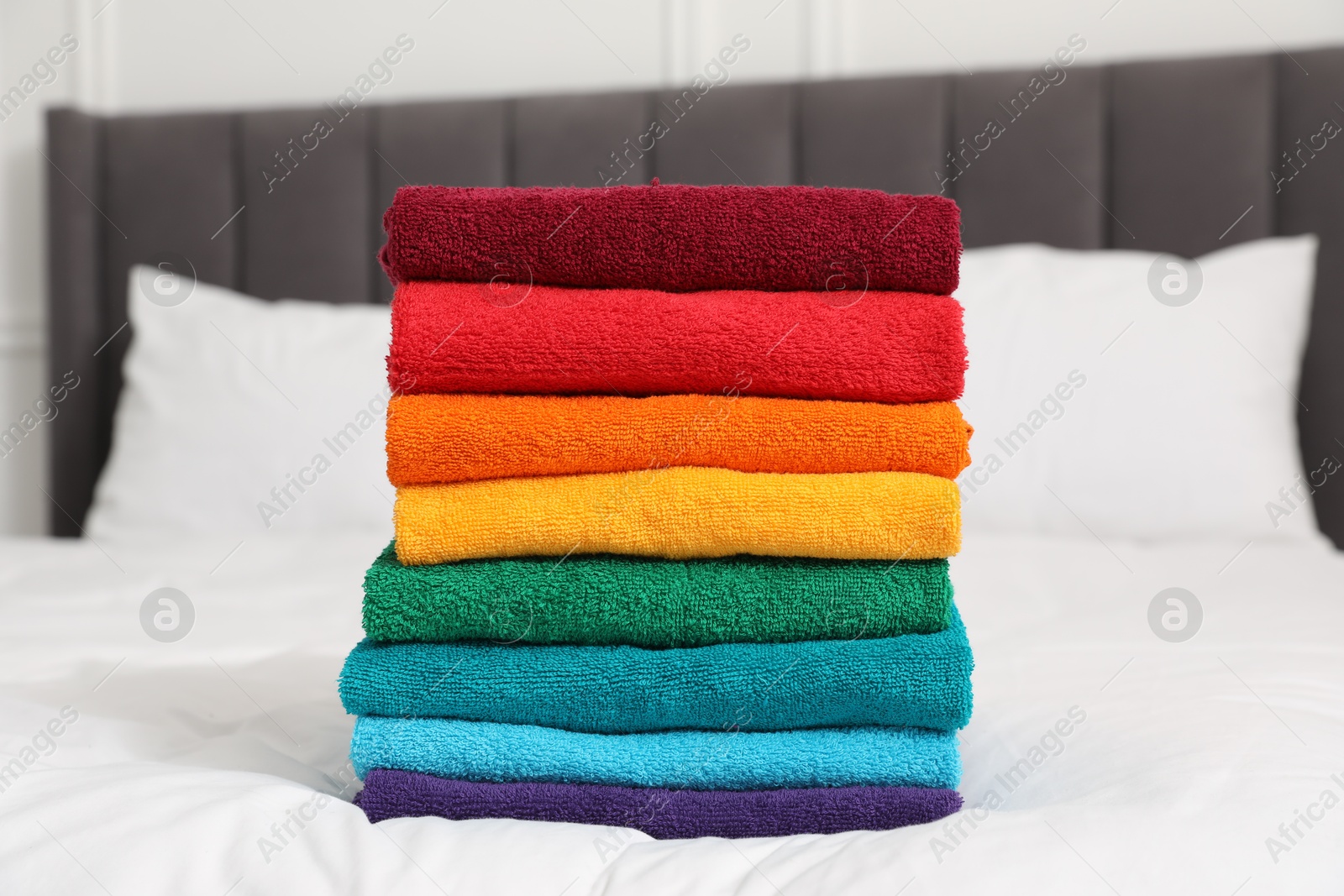 Photo of Stack of bright terry towels on bed indoors, closeup