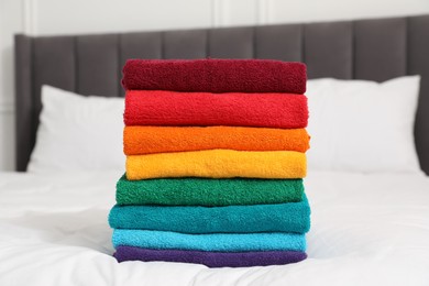 Photo of Stack of bright terry towels on bed indoors, closeup
