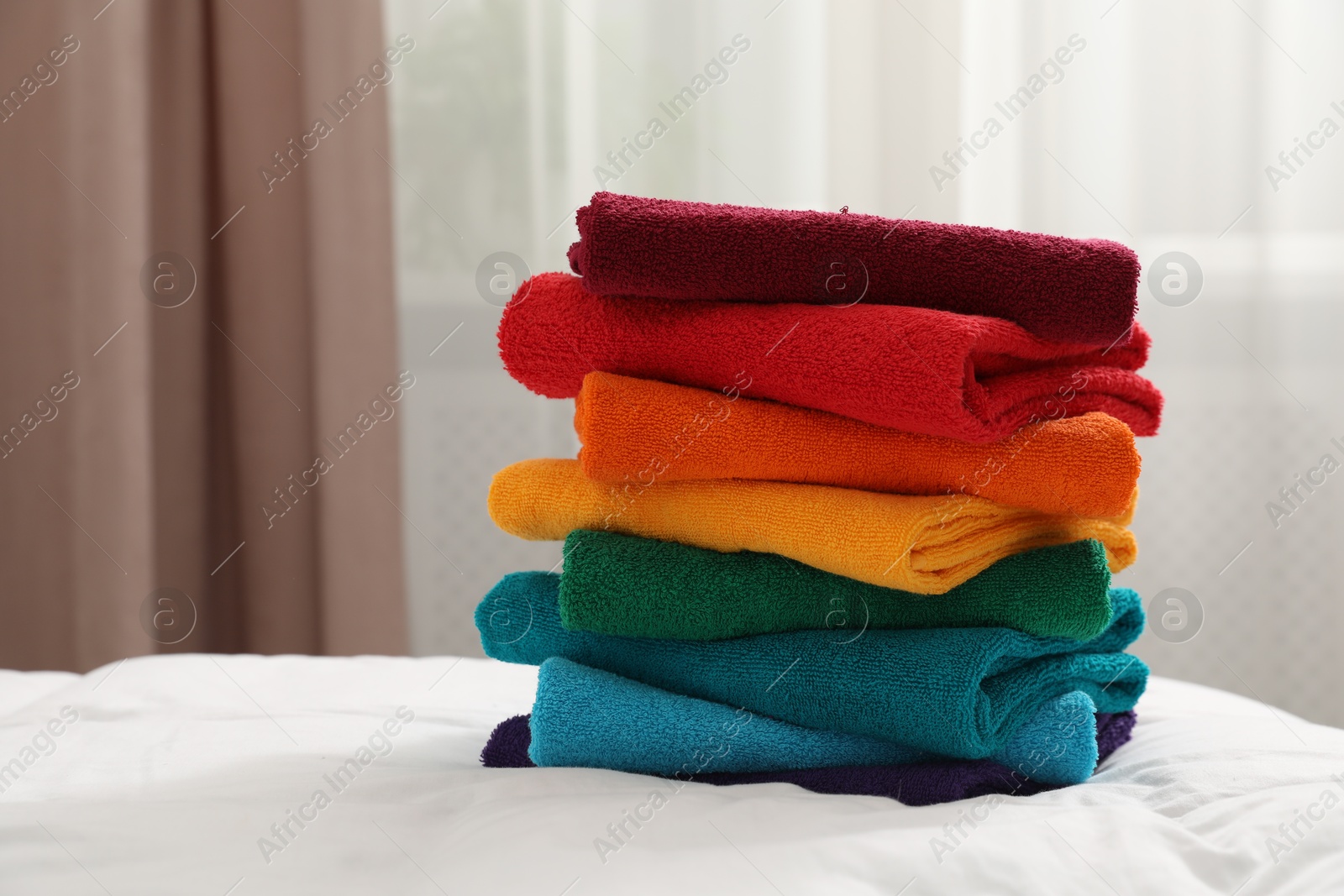 Photo of Stack of bright terry towels on bed indoors, closeup