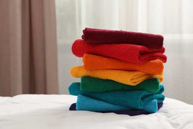 Photo of Stack of bright terry towels on bed indoors, closeup