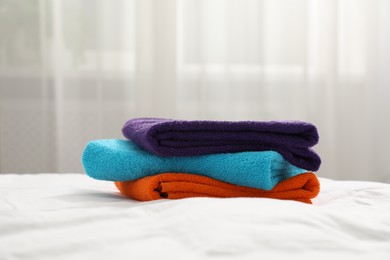 Photo of Stack of bright terry towels on bed indoors, closeup