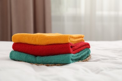 Photo of Stack of bright terry towels on bed indoors, closeup