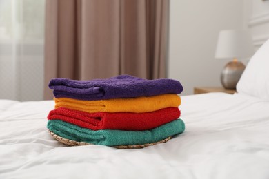Photo of Stack of bright terry towels on bed indoors, closeup