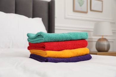 Photo of Stack of bright terry towels on bed indoors, closeup