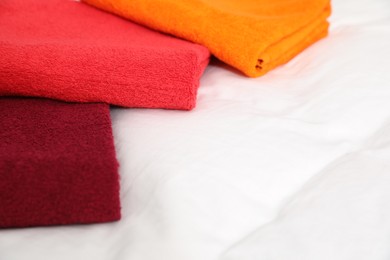 Photo of Bright terry towels and plumeria flowers on bed linens, closeup