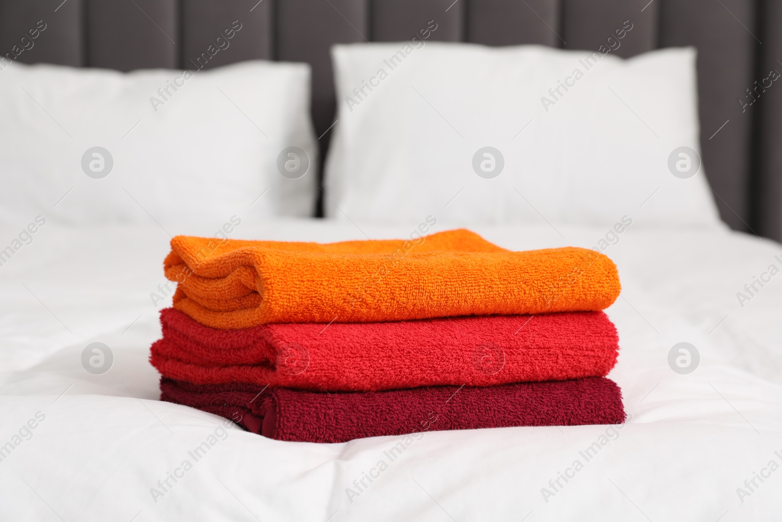 Photo of Stack of bright terry towels on bed, closeup