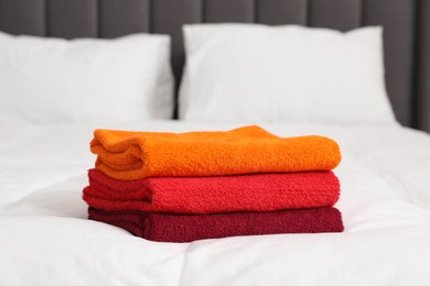 Photo of Stack of bright terry towels on bed, closeup