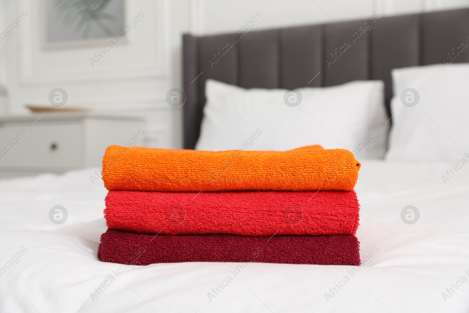 Photo of Stack of bright terry towels on bed indoors, closeup
