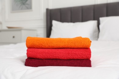 Photo of Stack of bright terry towels on bed indoors, closeup