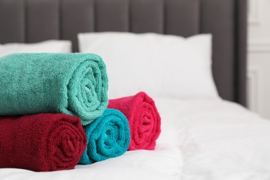 Photo of Bright terry towels on bed indoors, closeup. Space for text