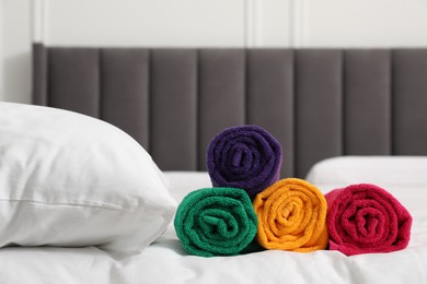 Photo of Bright terry towels and pillow on bed indoors, closeup