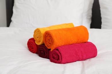 Photo of Rolled bright terry towels on bed linens, closeup