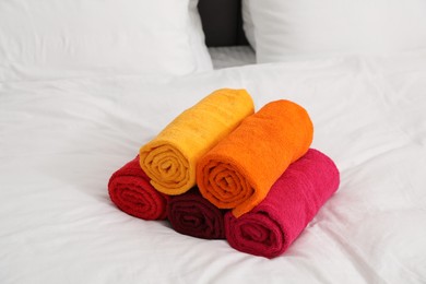 Photo of Rolled bright terry towels on bed linens, closeup