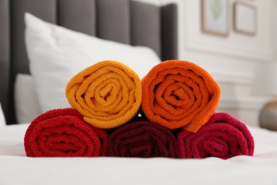 Photo of Rolled bright terry towels on bed indoors, closeup