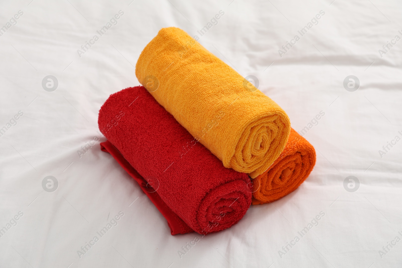 Photo of Bright terry towels on bed linens, closeup