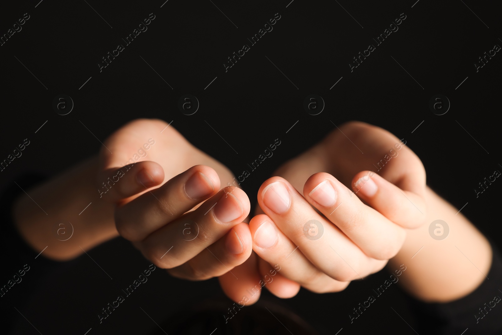 Photo of Woman holding something on black background, closeup