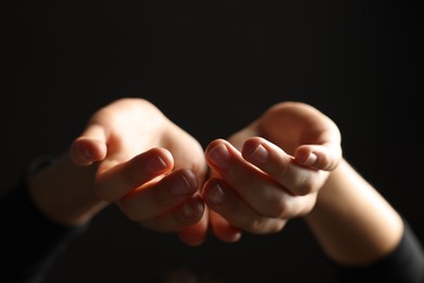Photo of Woman holding something on black background, closeup