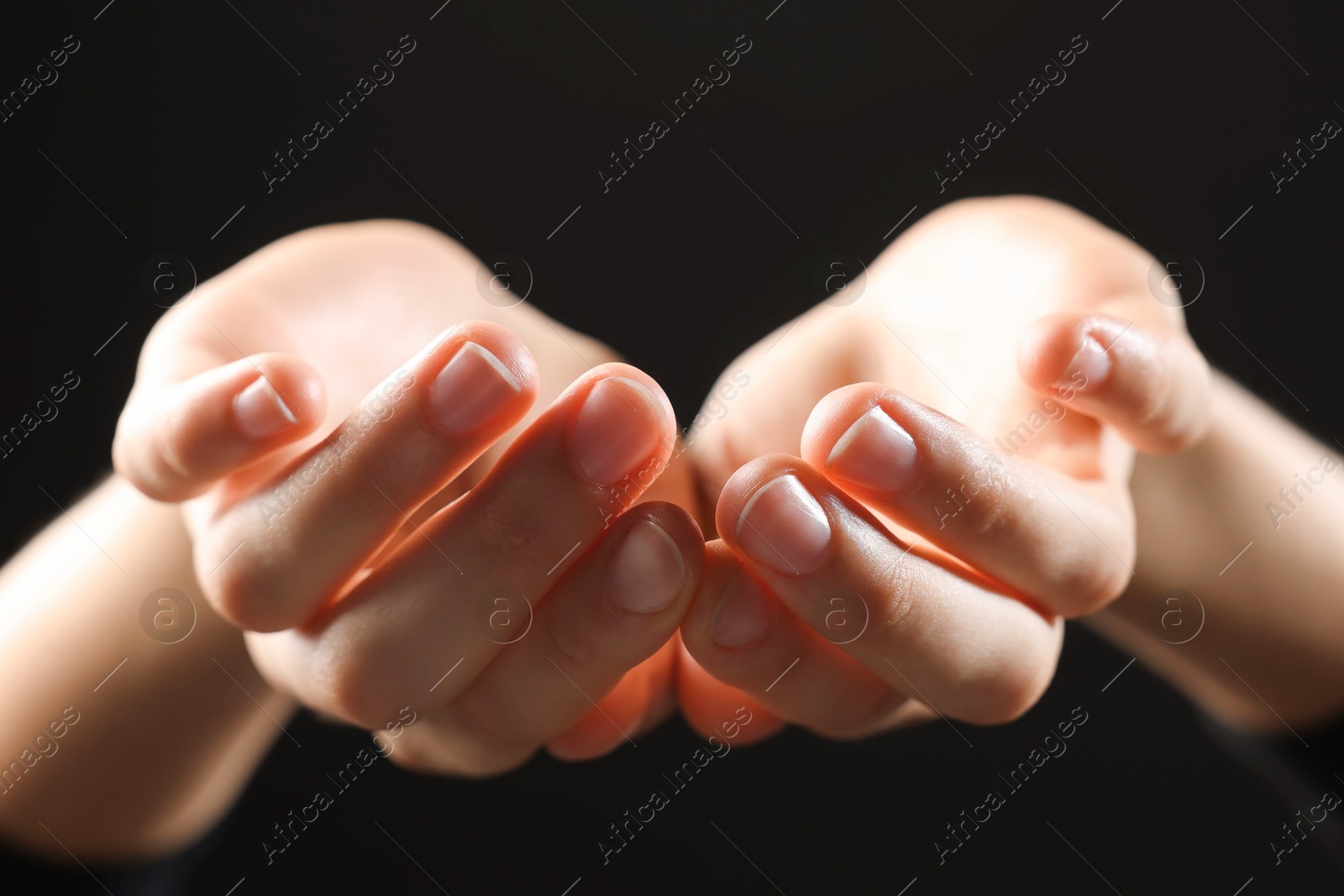 Photo of Woman holding something on black background, closeup