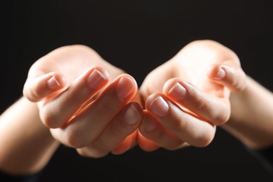 Photo of Woman holding something on black background, closeup