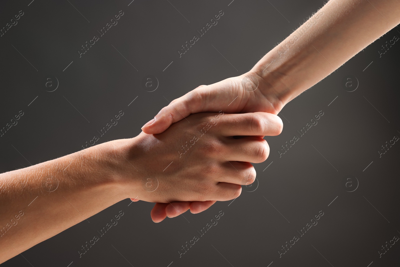 Photo of People holding hands on grey background, closeup
