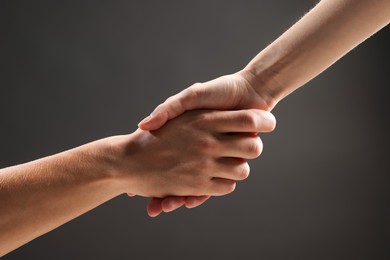 Photo of People holding hands on grey background, closeup