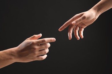 Photo of People joining hands on black background, closeup