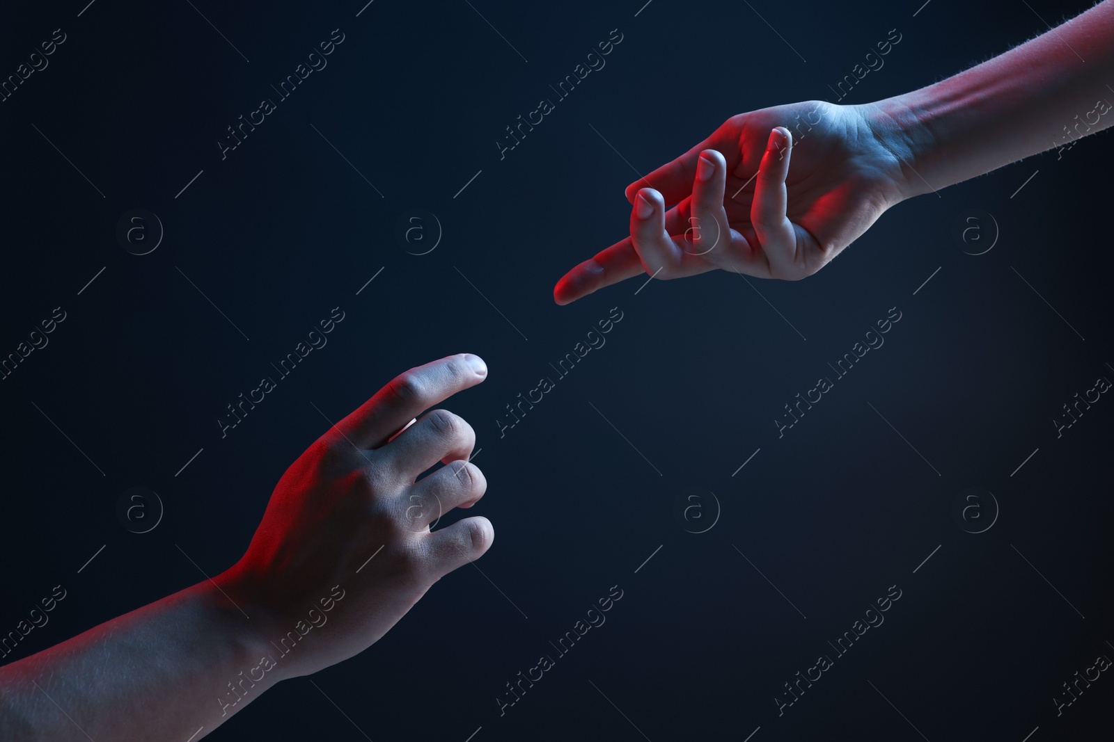 Photo of People joining hands on dark blue background, closeup
