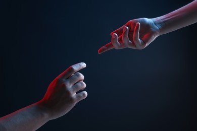 Photo of People joining hands on dark blue background, closeup