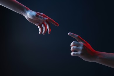 Photo of People joining hands on dark blue background, closeup