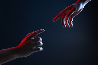 Photo of People joining hands on dark blue background, closeup