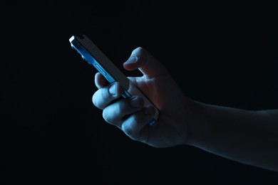 Photo of Man with modern smartphone on black background, closeup