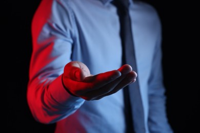 Photo of Man holding something on black background, closeup