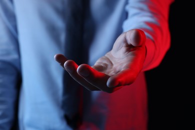 Photo of Man holding something on black background, closeup