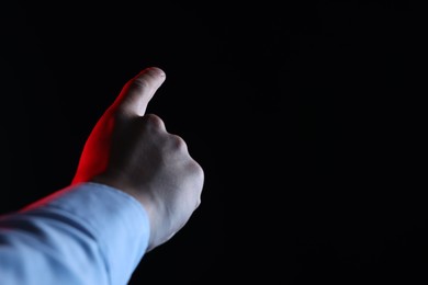 Photo of Man touching something on black background, closeup. Space for text