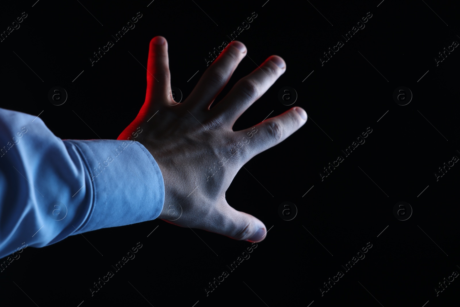 Photo of Man touching something on black background, closeup. Space for text