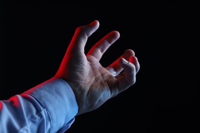 Photo of Man holding something on black background, closeup