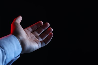 Photo of Man holding something on black background, closeup. Space for text