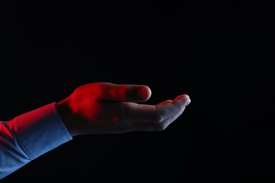Photo of Man holding something on black background, closeup. Space for text
