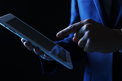 Photo of Man with modern tablet on black background, closeup